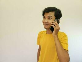 Portrait of a cheerful young asian man on call against grey background photo