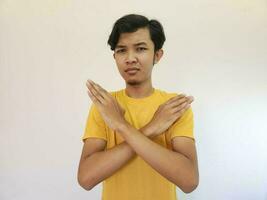 Portrait of young handsome Asian man showing STOP or Rejection expression crossing arms doing negative sign, angry face, isolated blue color background photo