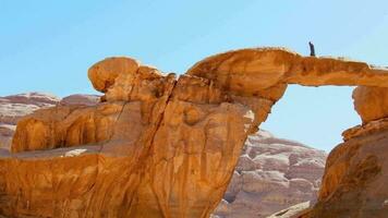 Bottom view arab bedouin guide walk stand on famous arch bridge in wadi rum desert pose and enjoy panoramic view of scenic rock formations video