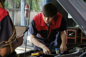 Two professional automotive mechanical partners check and repair an EV car battery and hybrid engine at a maintenance garage, expert electric vehicle service, and fixing occupations auto industry. photo