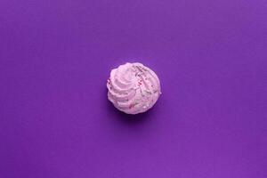 Single delicious purple meringues on purple background copy space photo