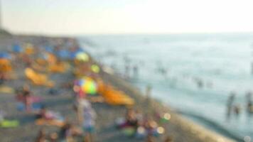 Static copy space blurry background tourist on crowded summer beach by sea relax. Intentional blur effect filter video