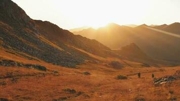 uomo e donna escursionisti nel distanza escursione su pista all'aperto su bellissimo tramonto nel autunno insieme. lento movimento contro sole attivo persone su trekking nel Caucaso montagne video