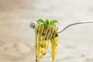 Spaghetti with pesto sauce and basil leaf on the fork photo