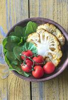 Baked cauliflower with cherry tomatoes and fresh spinach photo
