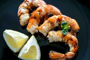 Fried shrimps with lemon wedges on the black background photo