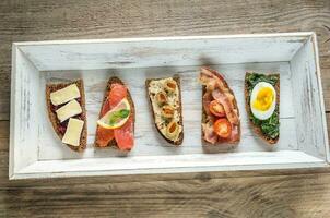 Bruschetta with different toppings on the wooden tray photo
