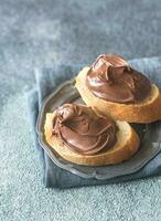 Slice of baguette with chocolate cream on the saucer photo