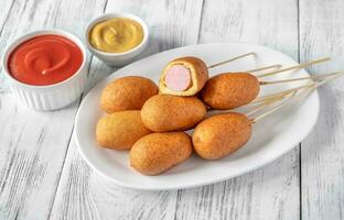 Corn dogs on white serving plate photo