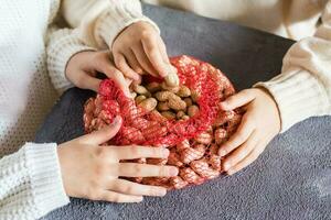 Children's hands reach unpeeled peanuts from a mesh bag on the table. Lifestyle photo