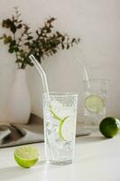 Sparkling mineral water with ice and lime in glasses for refreshment in the summer vertical view photo