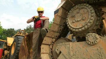 caucásico pesado equipo operador en su 30s quedarse Entre maquinaria. construcción industria. video