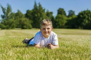 A cheerful child smiles with joy. I am happy to walk and play on the lawn in warm sunny weather in the park. the emotions of children on the face. photo