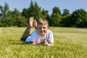 A cheerful child smiles with joy. I am happy to walk and play on the lawn in warm sunny weather in the park. the emotions of children on the face. photo