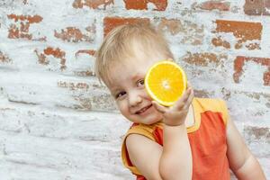 Portrait of child. Cute boy posing with an orange. The emotions of a child. photo