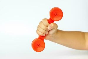 Red toy phone in the child's hand. Close-up of a child's hand. Isolated on a white background. The concept of an advertising banner. photo