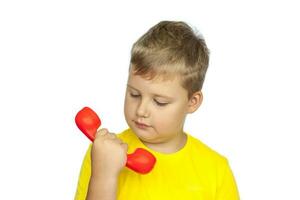 A boy in a yellow T-shirt on a white background with a red telephone receiver. The concept of a banner with information. Space for the text. photo