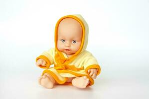 A toy baby in a bright dressing gown. Doll on a white background. photo