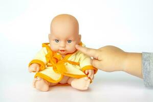 A child plays with a doll. Doll on a white background. Close-up of a child's hand. photo