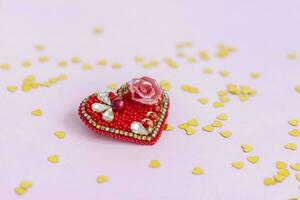 Pink background with gold hearts, sequins. Red heart made of beads. The concept of the Valentine's Day theme. Postcard, template, background for graphic works. photo