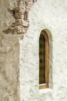 Architectural elements of the wall, windows with colored stained glass. An old wall with cracks. photo
