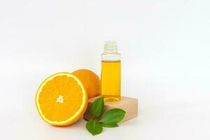 Orange oil for the body. Orange on a wooden pedestal on a white background. Organic SPA cosmetics with herbal ingredients. photo