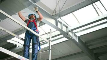 masculino construcción contratista en pie en andamio y instalando ventilación metal tubería dentro de nuevo edificio. video