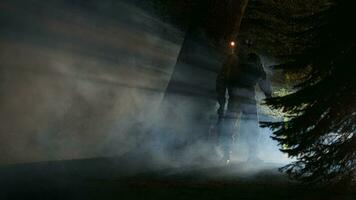 armé soldat avec fusil et lampe de poche dans foncé forêt couvert par fumée video