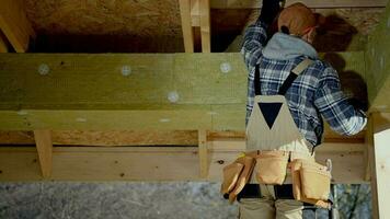 construção contratante trabalhador anexando blocos do isolamento mineral lã. video