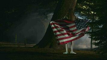 hermosa pequeño niña hilado alrededor participación y flotante americano bandera en parque. video