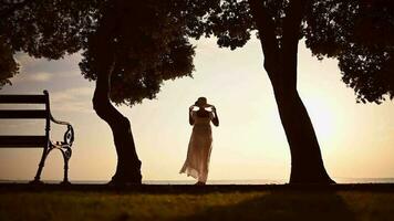 femme dans grand Soleil chapeau et blanc robe dans le tropical emplacement profiter le coucher du soleil video