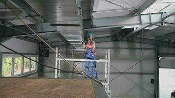 caucásico masculino construcción trabajador fijación partes de instalado aire acondicionamiento eje en techo de nuevo edificio. video