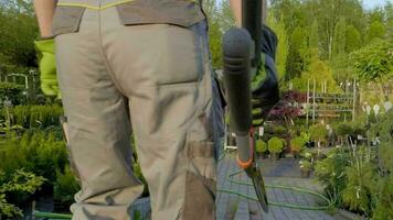 Gardener with Large Scissors Walking Trough the Garden Store Area video