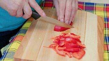 mayor caucásico mujer cortar dulce rojo campana pimienta en de madera corte tablero video