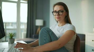 casualmente vestito donna con cuffie Lavorando con un' computer e smartphone a casa nel un' accogliente ambiente. a distanza opera video