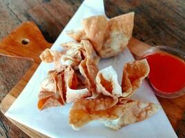 Set menu of fried dim sum served with chili sauce on wooden cutting board photo