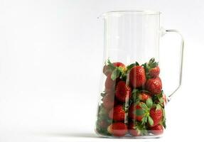 Red strawberries on a white background with copy space for your text. Ripe berry in a glass jar with highlights photo