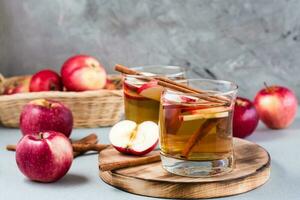 Homemade apple cider with cinnamon in glasses on a gray background. Warming winter drinks photo