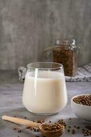 vegano Libre de lácteos alforfón Leche en un vaso y cereales en un cuenco en el mesa vertical ver foto
