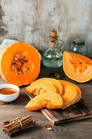 Pieces with ripe pumpkin seeds on a cutting board on a wooden table. Vegetarian food. Rustic style. Vertical view photo