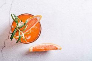 Close up of fresh grapefruit juice with rosemary and pieces of fruit in a glasses top view photo