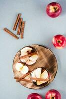 Fresh organic apple cider with cinnamon in glasses and apples on a gray background. Warming winter drinks. Top and vertical view photo