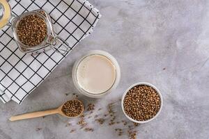 Vegan dairy-free buckwheat milk in a glass and cereals in a bowl on the table top view photo