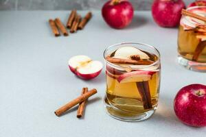 Homemade fresh apple cider with cinnamon in glass on a gray background. Warming winter drinks. Copy space photo