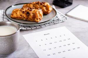 Calendar sheet for planning during a snack with latte and buns in fika time photo