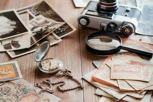 un reloj en un cadena, Envejecido rublo facturas, un película cámara y negro y blanco fotografias en un de madera mesa. Clásico colección y nostalgia para el pasado foto