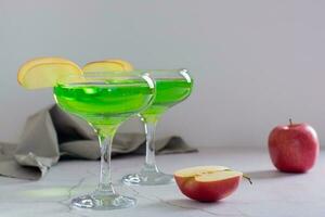 Homemade green apple martini cocktail with apple pieces in glasses photo