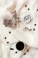 Inspirational still life - alarm clock, cup of coffee and dried flowers on a cozy white sweater. Time for rest and relaxation. Top and vertical view photo