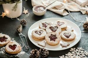 Ready Linzer cookies with berry jam on a plate on a dark background. Cooking Christmas treats. Lifestyle photo