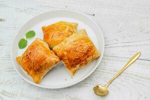 Banana Bolen Cake on a white plate on a wooden background. Bolen Pisang. photo